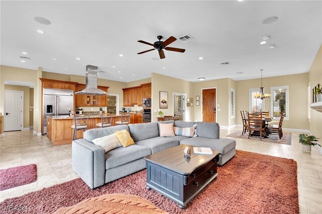 living room with ceiling fan with notable chandelier and light tile patterned floors