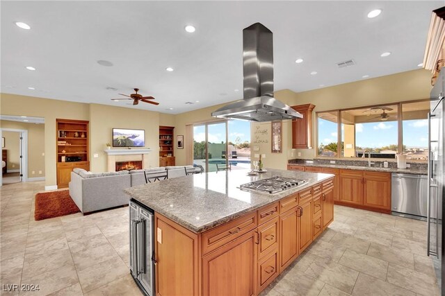 kitchen featuring stainless steel appliances, sink, ceiling fan, a kitchen island, and island range hood