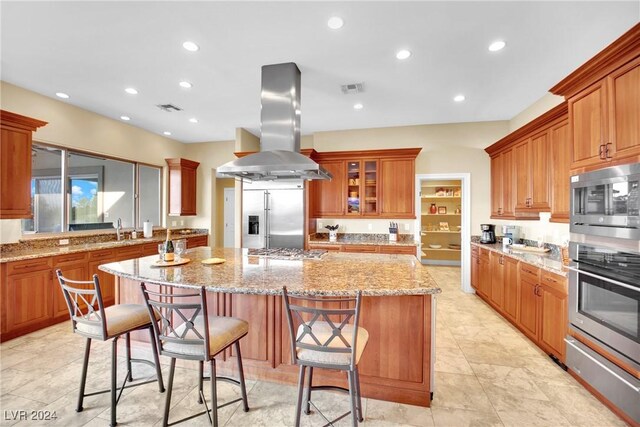 kitchen with built in appliances, light stone countertops, a kitchen island, and island range hood