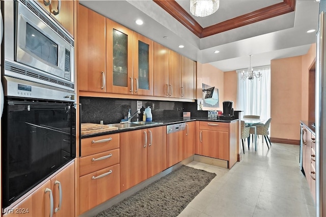 kitchen with crown molding, decorative light fixtures, appliances with stainless steel finishes, a notable chandelier, and sink