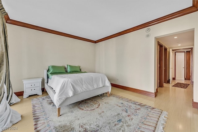 bedroom featuring ornamental molding and light hardwood / wood-style flooring