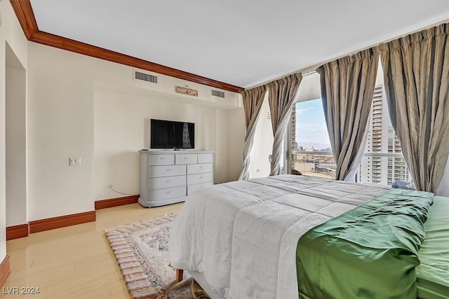 bedroom with ornamental molding and light wood-type flooring