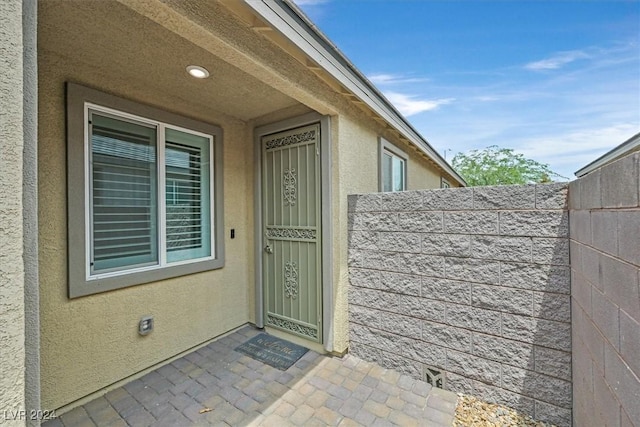 property entrance featuring fence and stucco siding