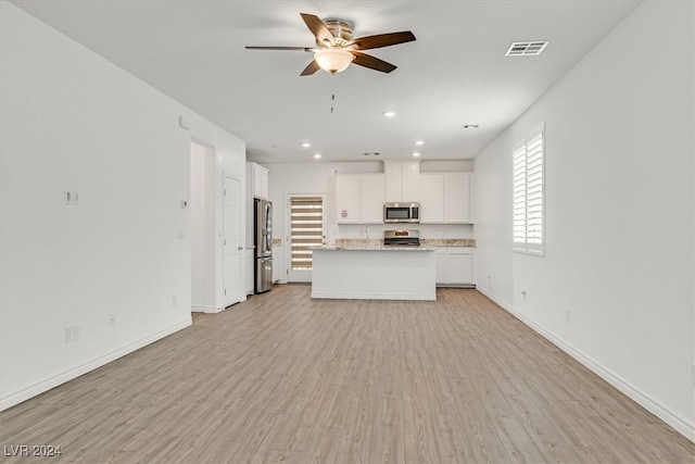 kitchen with light wood-type flooring, white cabinetry, stainless steel appliances, light stone counters, and ceiling fan