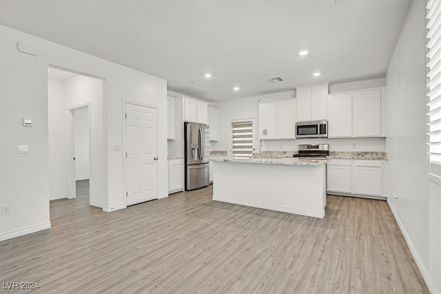 kitchen with a center island with sink, stainless steel appliances, white cabinets, and light hardwood / wood-style floors