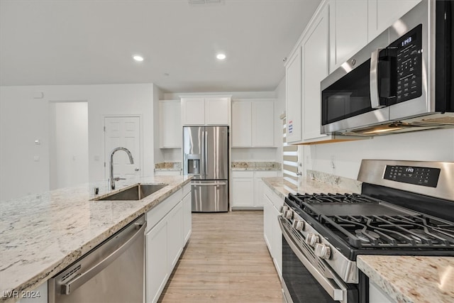 kitchen featuring white cabinets, light wood-type flooring, light stone counters, stainless steel appliances, and sink