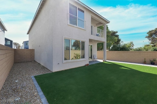 rear view of property with a balcony and a yard