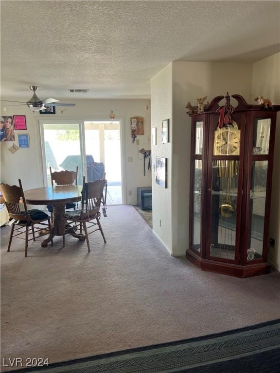 carpeted dining space featuring visible vents, ceiling fan, and a textured ceiling