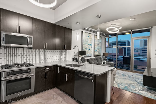 kitchen featuring tasteful backsplash, light hardwood / wood-style flooring, kitchen peninsula, sink, and appliances with stainless steel finishes