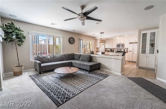 carpeted living room featuring ceiling fan and sink