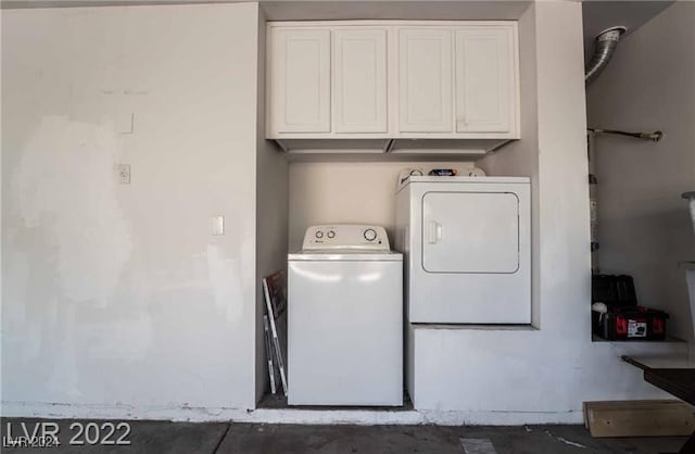 clothes washing area with cabinets and washing machine and dryer