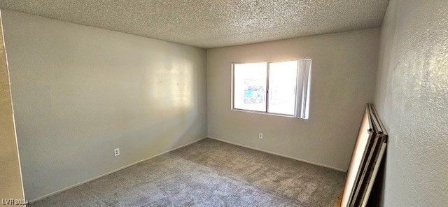 spare room with light colored carpet and a textured ceiling