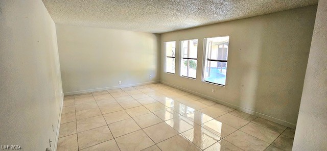 spare room featuring a textured ceiling and light tile patterned flooring