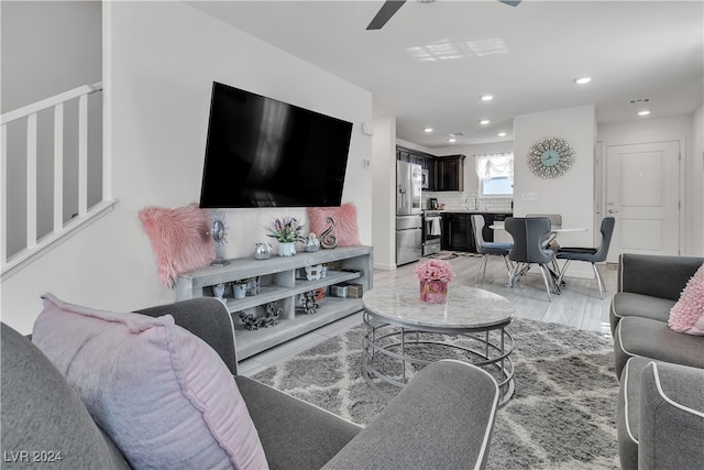 living room featuring light hardwood / wood-style flooring, sink, and ceiling fan