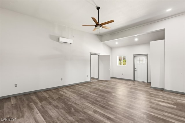 unfurnished room featuring a wall mounted AC, ceiling fan, and hardwood / wood-style flooring