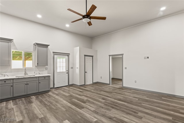 interior space with ceiling fan, sink, hardwood / wood-style floors, and a high ceiling