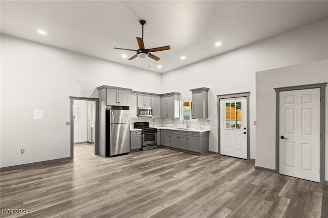 kitchen featuring gray cabinetry, hardwood / wood-style floors, stainless steel appliances, sink, and ceiling fan