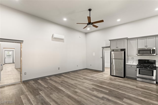 kitchen with hardwood / wood-style floors, gray cabinetry, stainless steel appliances, and ceiling fan