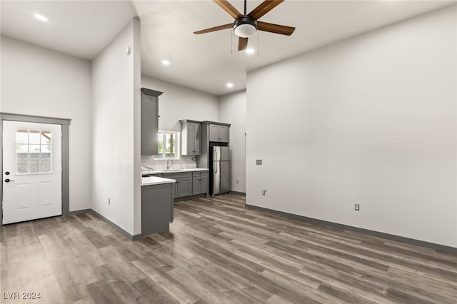 kitchen with gray cabinetry, hardwood / wood-style flooring, sink, stainless steel fridge, and ceiling fan