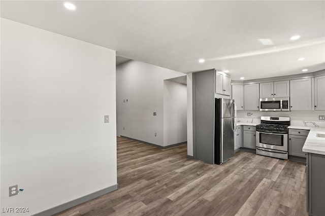 kitchen with gray cabinets, appliances with stainless steel finishes, and hardwood / wood-style flooring