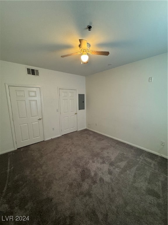 unfurnished bedroom featuring electric panel, dark carpet, and ceiling fan