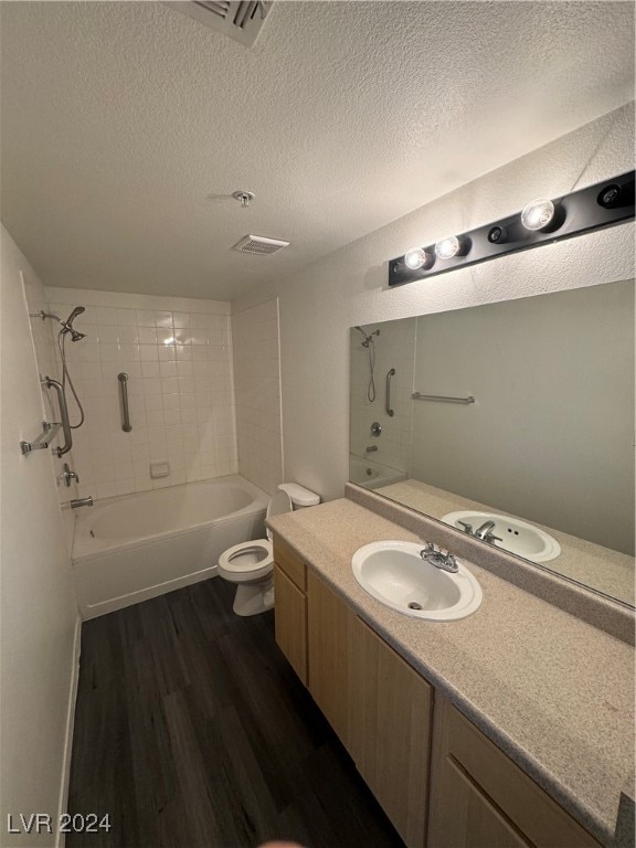 full bathroom featuring tiled shower / bath, toilet, wood-type flooring, vanity, and a textured ceiling