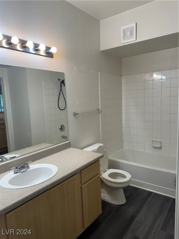 full bathroom with wood-type flooring, toilet, tiled shower / bath combo, and vanity