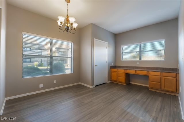 unfurnished office with built in desk, dark hardwood / wood-style flooring, and a notable chandelier