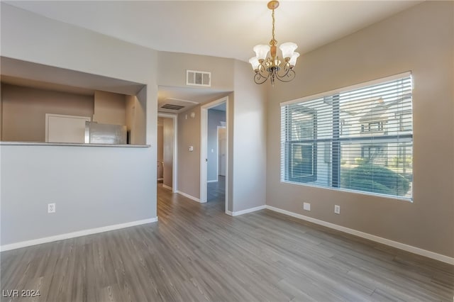 spare room with hardwood / wood-style floors and a notable chandelier