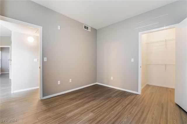 unfurnished bedroom featuring hardwood / wood-style floors, a spacious closet, and a closet