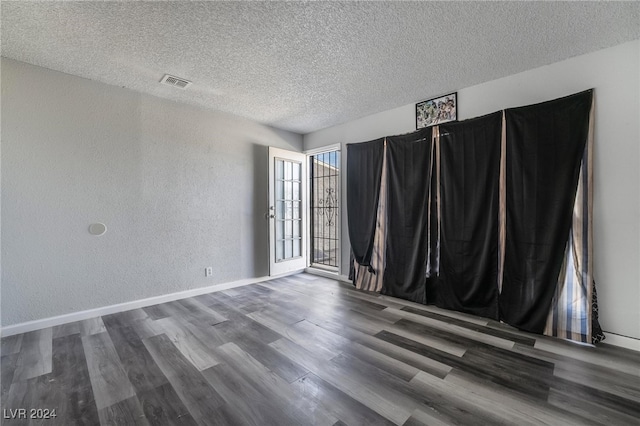 unfurnished room featuring a textured ceiling and dark hardwood / wood-style floors