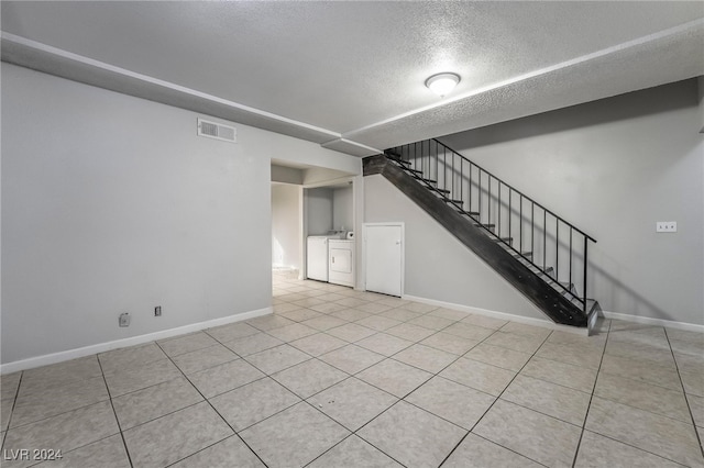 unfurnished living room with a textured ceiling, washing machine and dryer, and light tile patterned flooring