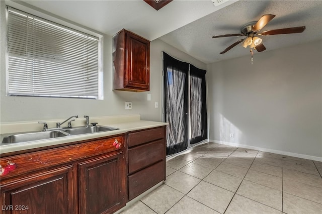 kitchen with ceiling fan, light tile patterned floors, a textured ceiling, and sink