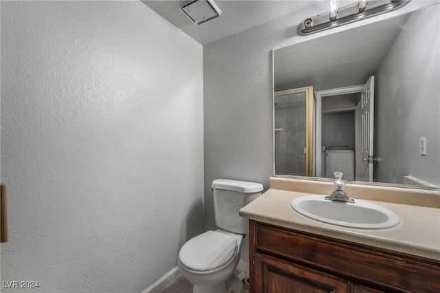 bathroom featuring a shower with shower door, vanity, and toilet