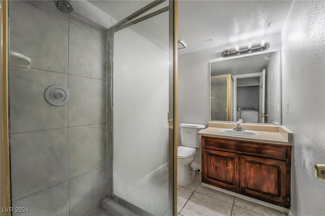 bathroom featuring vanity, a textured ceiling, a shower, tile patterned floors, and toilet