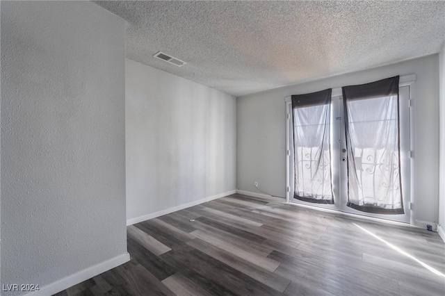 unfurnished room featuring a textured ceiling and dark hardwood / wood-style flooring