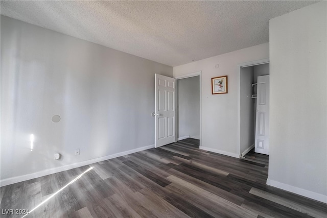 empty room featuring a textured ceiling and dark wood-type flooring