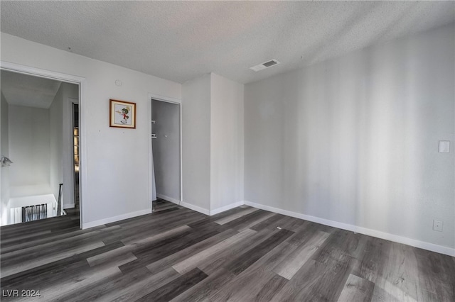 spare room with a textured ceiling and dark wood-type flooring