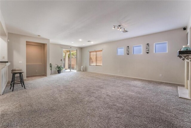 unfurnished living room with a fireplace, track lighting, and light carpet