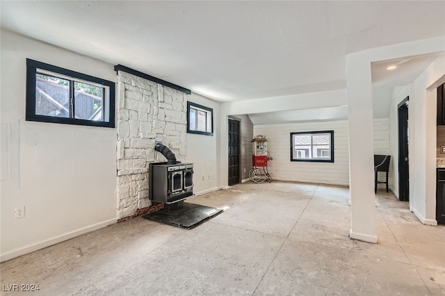 unfurnished living room featuring plenty of natural light and a wood stove