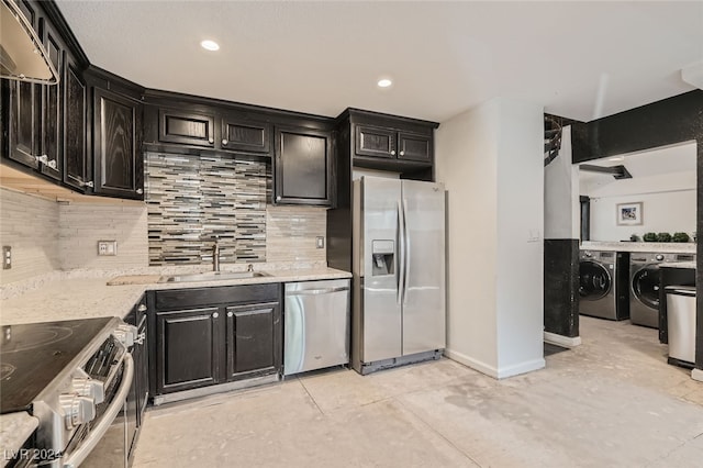 kitchen with stainless steel appliances, sink, wall chimney range hood, washing machine and clothes dryer, and tasteful backsplash