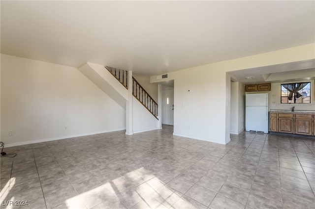 unfurnished living room featuring light tile patterned flooring and sink