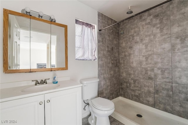 bathroom featuring a tile shower, tile patterned flooring, vanity, and toilet