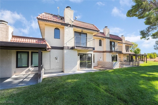 back of property featuring a lawn, a balcony, and a patio area