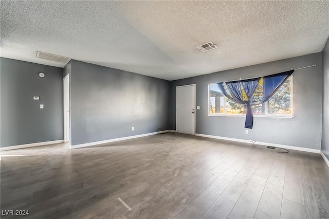 empty room featuring wood-type flooring and a textured ceiling