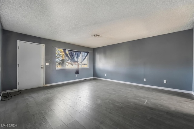 spare room featuring dark wood-type flooring and a textured ceiling