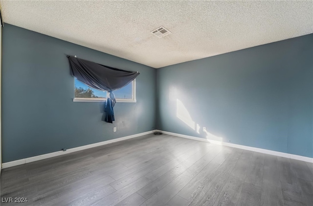 empty room with a textured ceiling and dark hardwood / wood-style flooring