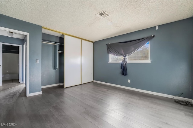 unfurnished bedroom with a textured ceiling, hardwood / wood-style flooring, and a closet