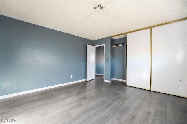 unfurnished bedroom with hardwood / wood-style floors, a textured ceiling, and a closet