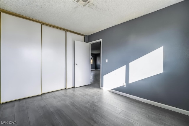 spare room with dark hardwood / wood-style floors and a textured ceiling